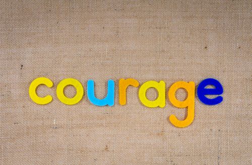 Free Brightly colored letters spelling 'Courage' on a burlap background, conveying a message of bravery. Stock Photo