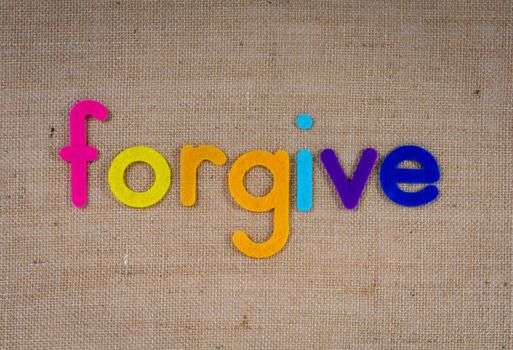 Vibrant felt letters spelling 'forgive' on a burlap background.