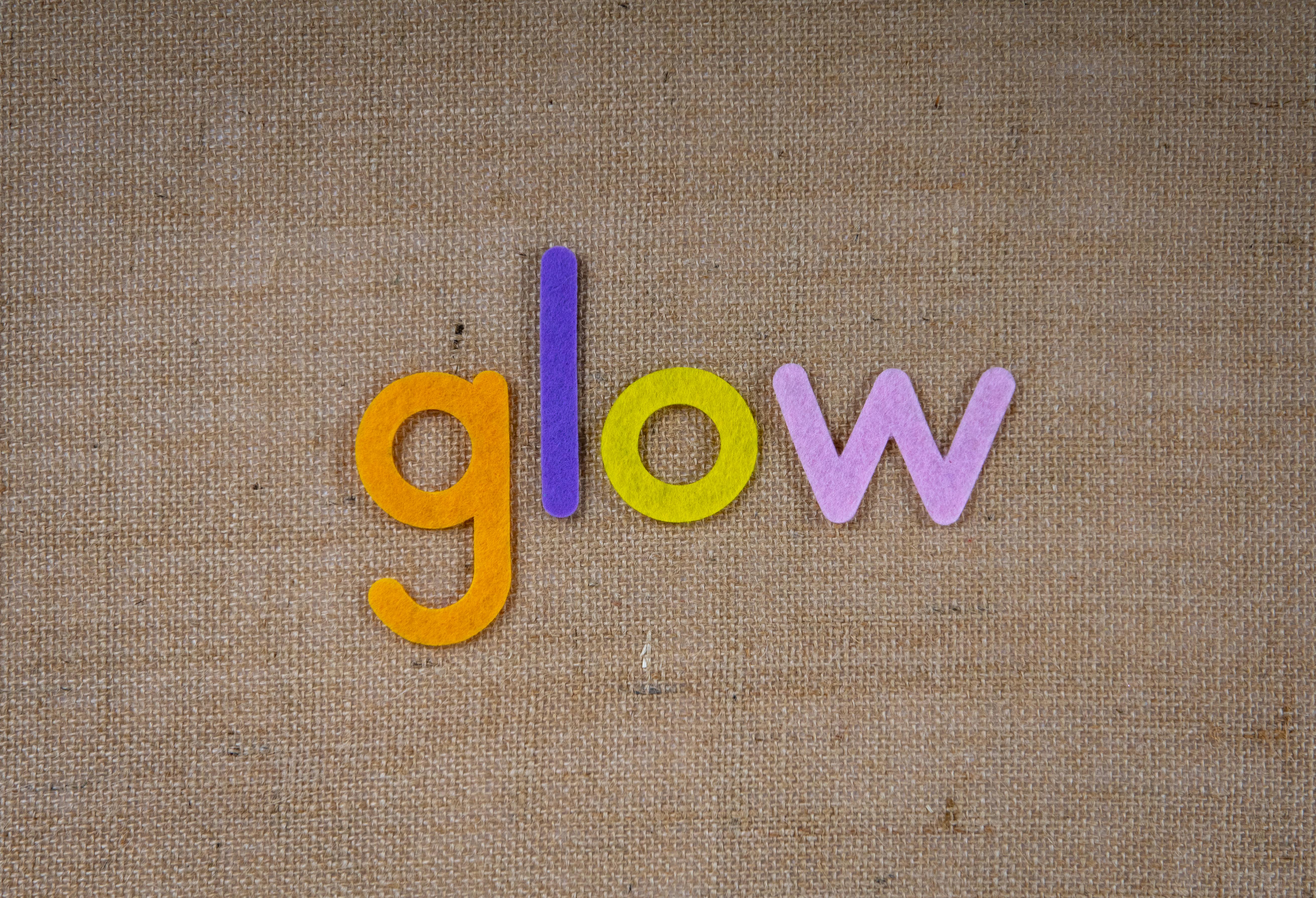 在纹理织物背景上，彩色毛毡字母拼出“发光”二字