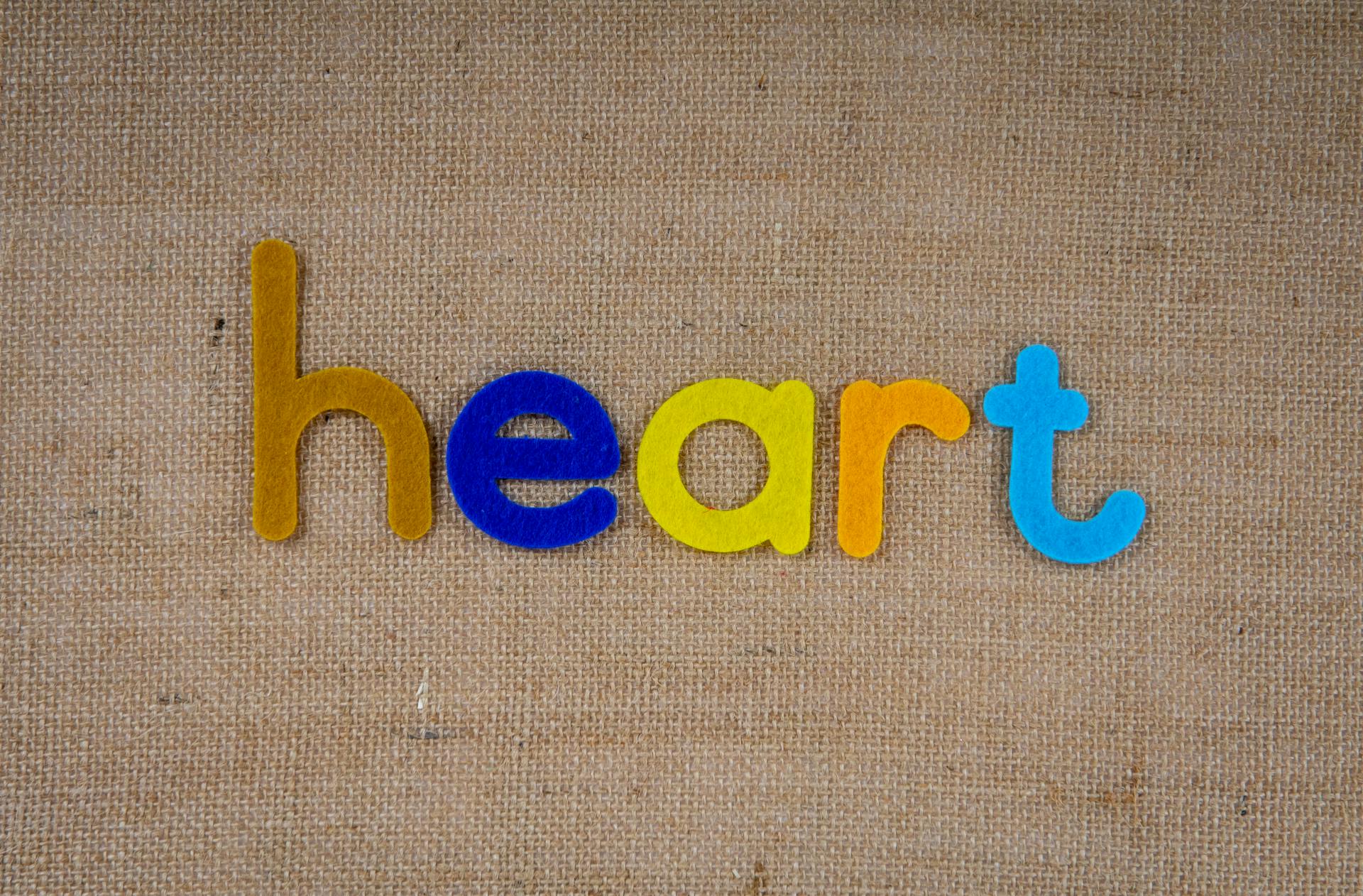 Colorful letters spelling 'heart' on a textured burlap background, perfect for creative projects.