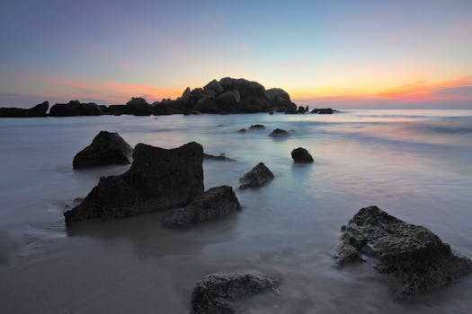 黎明时分，宁静的海景中岩石与平静的海洋在淡淡的天空下相映成趣