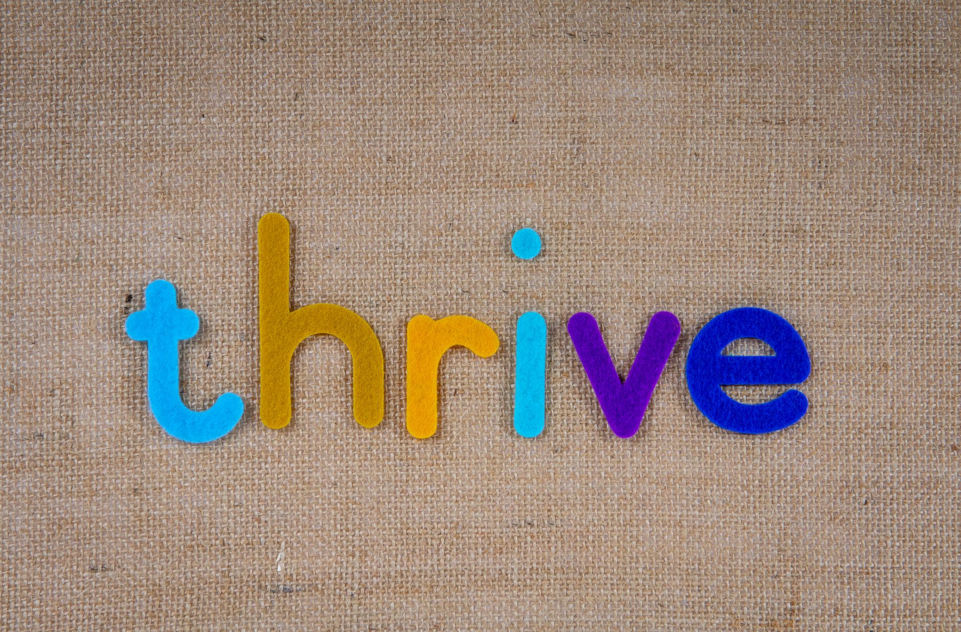 Bright felt letters spelling 'thrive' on a beige fabric background offer inspiration.