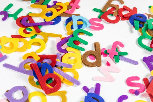 Bright and colorful felt letters scattered on a white background, perfect for educational activities.