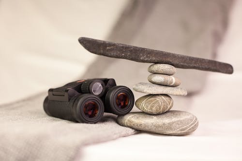 Black Binoculars on White Textile Near Stones