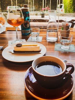 A warm cafe scene with coffee, dessert, and drinks on a wooden table, perfect for relaxation.