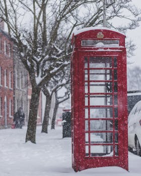 Classic red telephone booth in a snowy street scene in Bridport, United Kingdom.