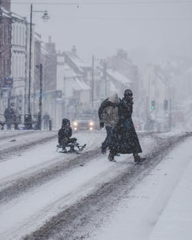 A family enjoying a walk on a snowy street in Bridport, England during heavy snowfall.