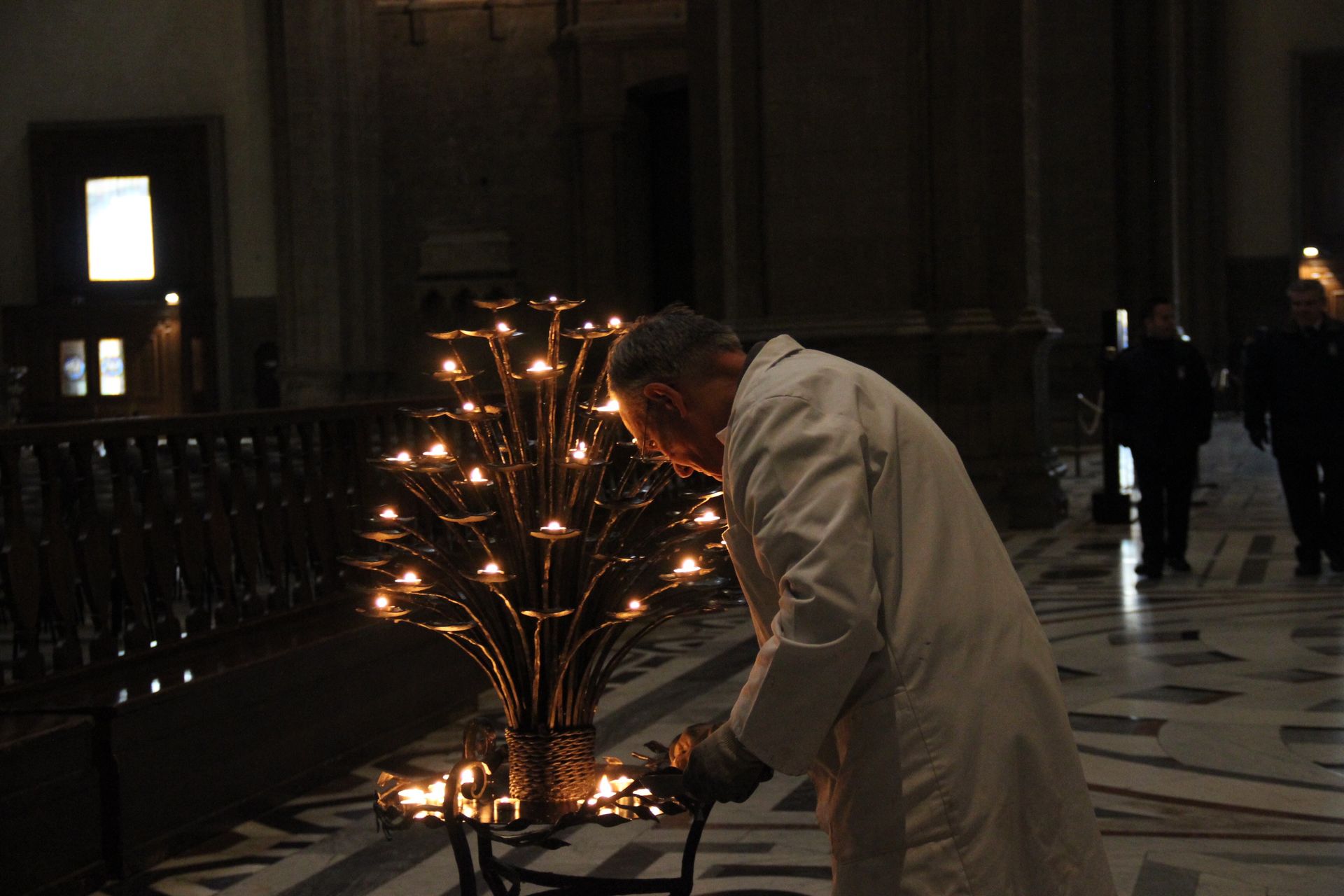 An elderly man lights candles inside a historic church in Florence, Italy.