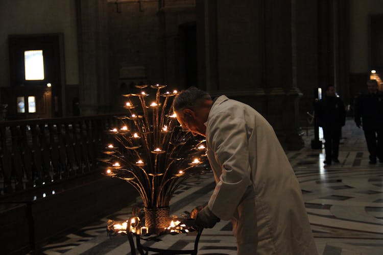 A Man Lighting Candles Inside A Church In Florence, Italy