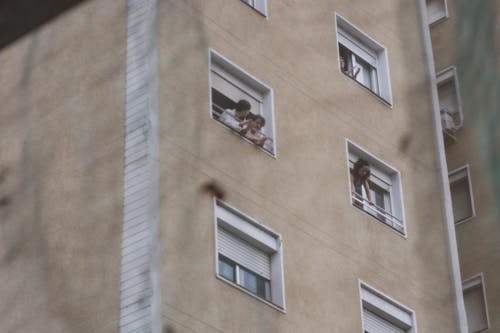 People Looking Out of Their Windows in a Block of Flats