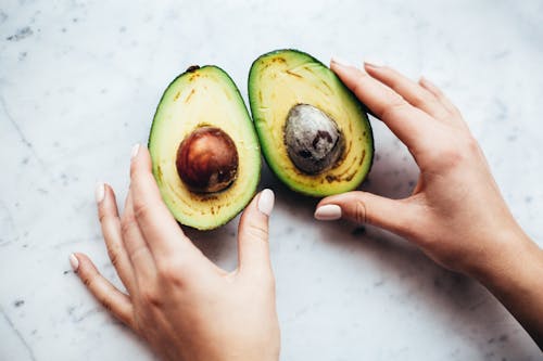 Person Holding Sliced Avocado