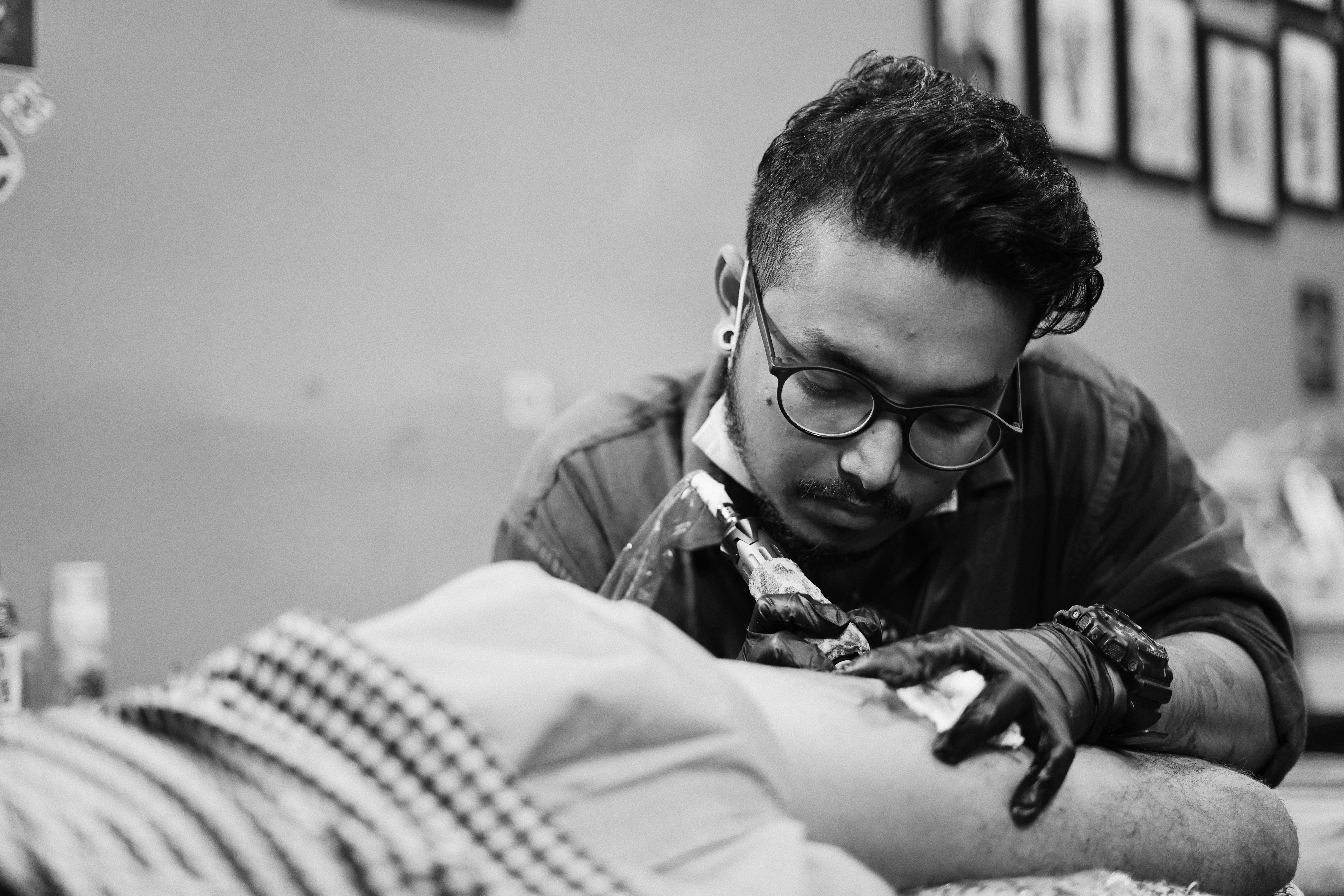 Focused master doing tattoo to crop client · Free Stock Photo
