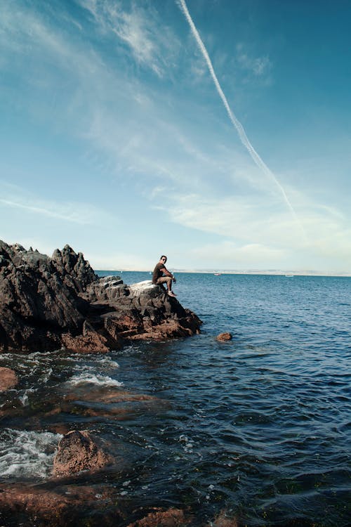 A Person Sitting on a Coastal Landform in Playa La Caleta Colorada
