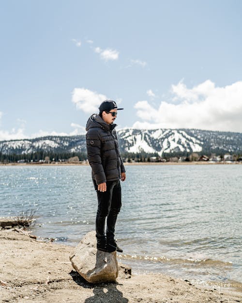 Man in Black Jacket Standing on Brown Rock