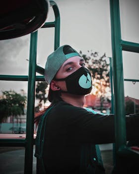 Confident young guy in cap and protective mask with bear muzzle looking at camera in park