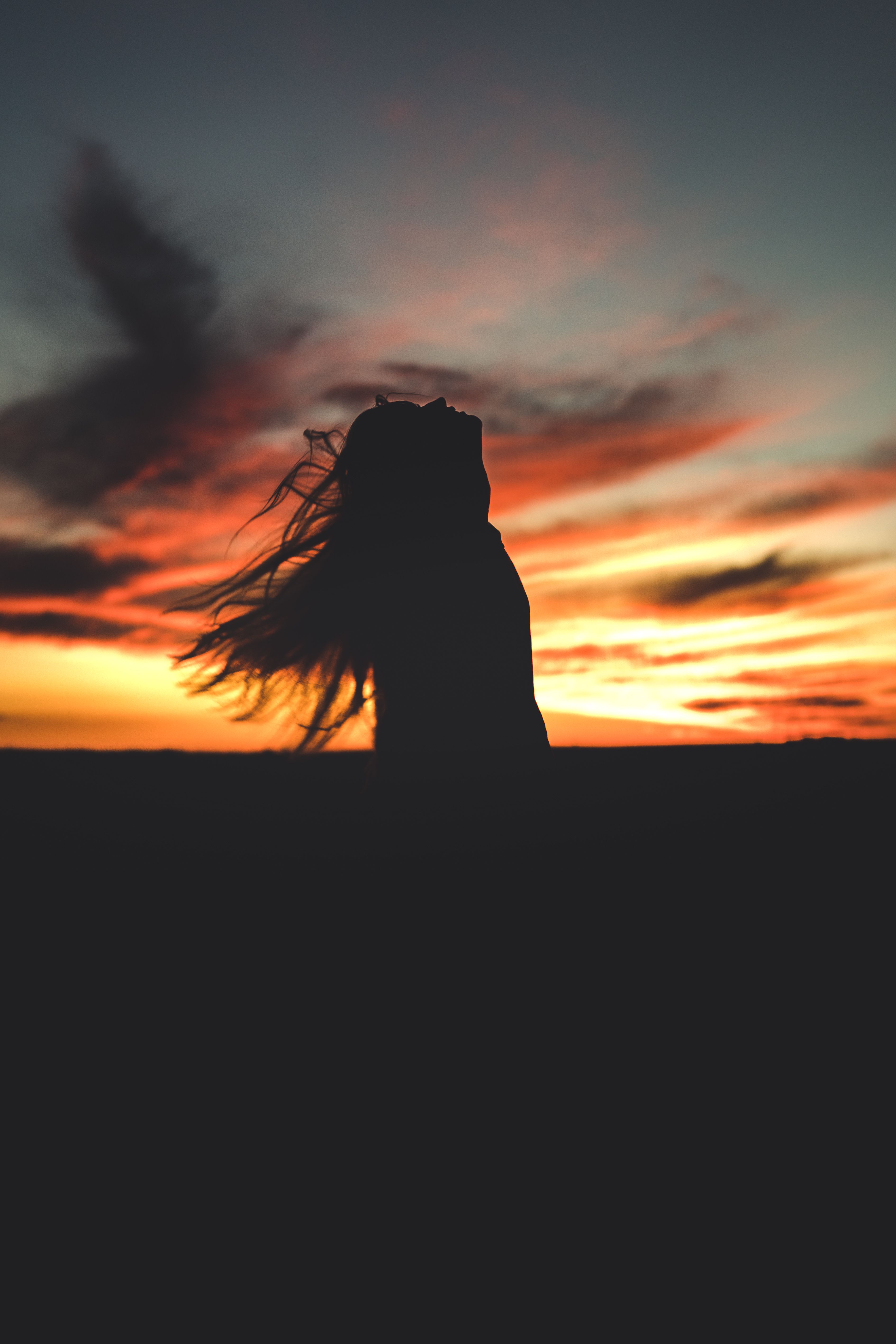 Silhouette of woman against sunset sky · Free Stock Photo
