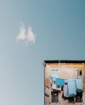 A weathered apartment building with laundry drying under a clear blue sky.
