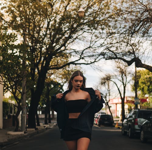 A Woman in Black Tube Top and Long Sleeves Standing on the Street