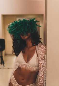 Stylish portrait of a woman in lace lingerie and feather mask, exuding mystery and elegance.