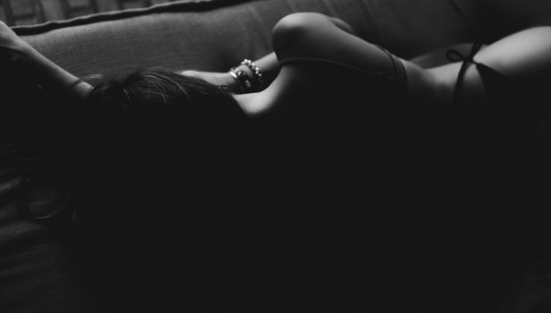 A black and white artistic photo capturing the silhouette of a woman in an intimate setting.