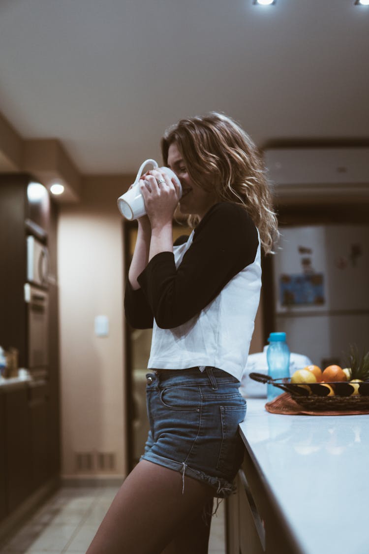 Woman Leaning On Kitchen Island While Holding A Mug