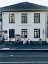 Old building facade near city road and women on bench