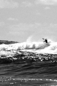 Grayscale Photo of Man Surfing on Sea Waves