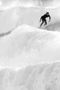 Black and white surfer balancing on splattering ocean waves while practicing extreme sport in daylight in stormy weather