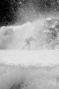 Black and white silhouette of faceless sportsman practicing surfing on foamy sea with splashing water in stormy weather