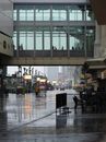 现代城市景观中，一条多雨的街道和一座玻璃人行天桥映衬着人的剪影