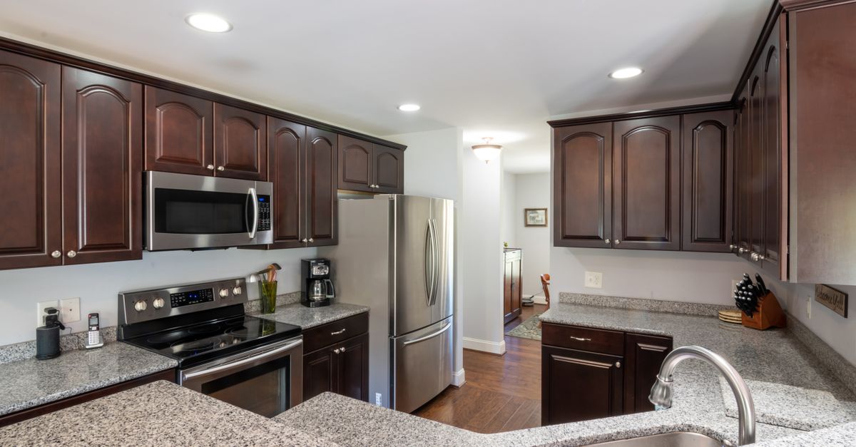 Elegant kitchen featuring dark wooden cabinets, granite countertops, and stainless steel appliances in a contemporary setting.