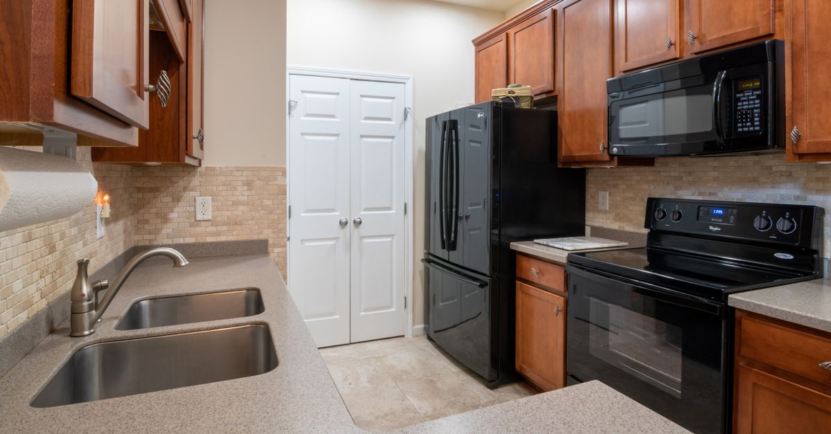 A contemporary kitchen featuring wooden cabinets, modern appliances, and a marble countertop.