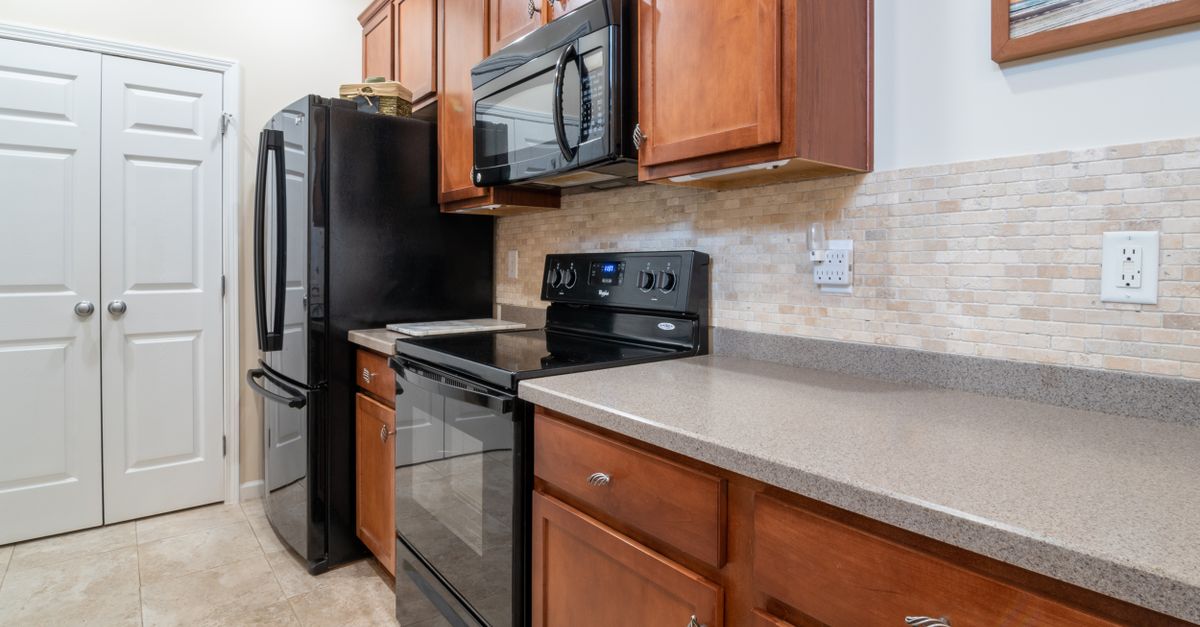 A sleek and modern kitchen interior featuring stainless steel appliances, wooden cabinets, and a marble countertop.