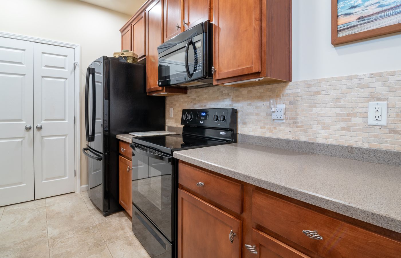 A sleek and modern kitchen interior featuring stainless steel appliances, wooden cabinets, and a marble countertop.