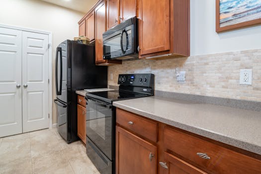 A sleek and modern kitchen interior featuring stainless steel appliances, wooden cabinets, and a marble countertop.
