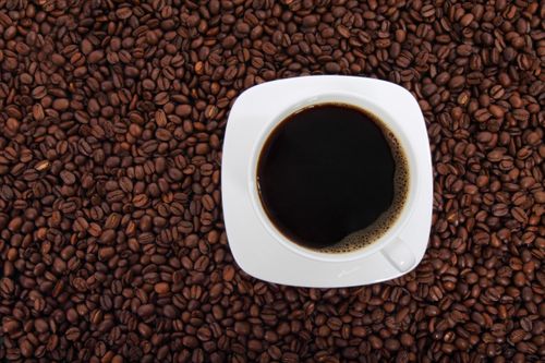Free A fresh cup of black coffee in a white saucer set against a rich bed of coffee beans. Stock Photo
