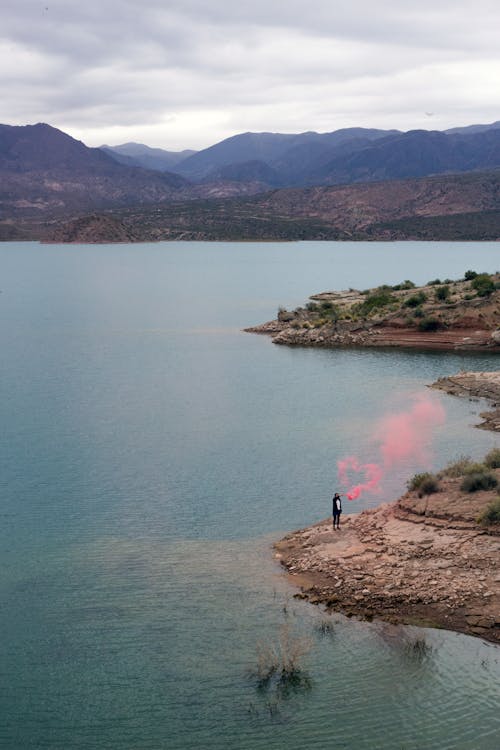 Unrecognizable person in pink flare smoke on amazing seaside