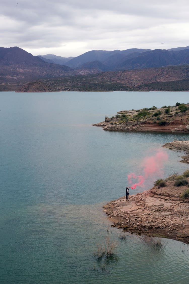 Unrecognizable Person In Pink Flare Smoke On Amazing Seaside