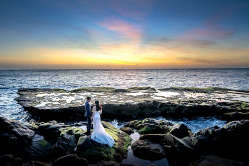 Free Photo of Couple Standing on Rocky Seashore Stock Photo