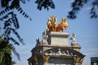 From below of top of Golden fountain located near green trees under blue sky with clouds in sunny day