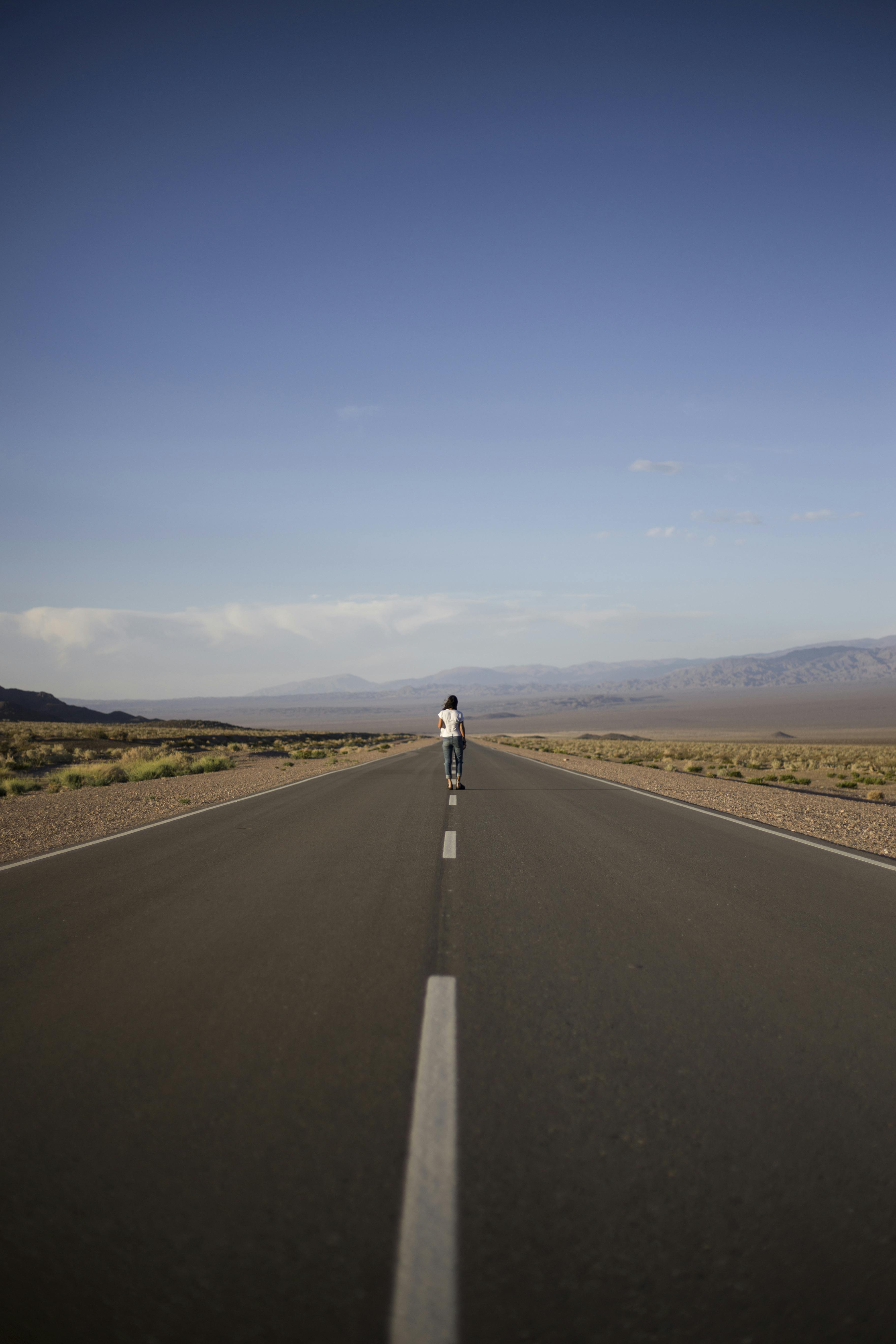 在晴朗的日子里，站在乡村偏远空旷的柏油路中央，面向岩石高地