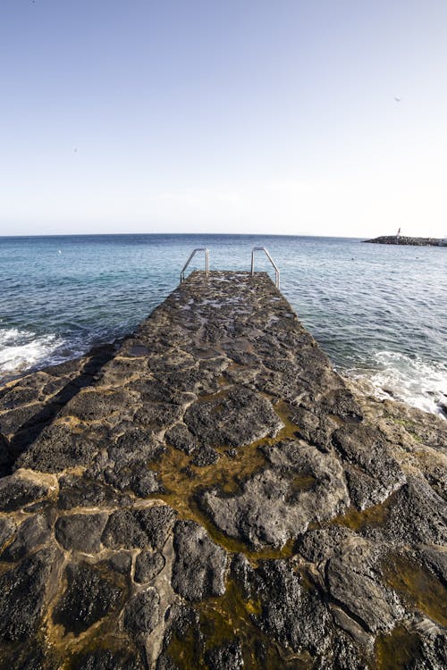 Stone pier against endless calm sea on clear day