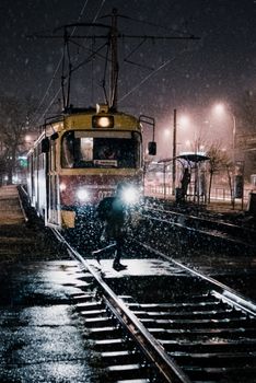 雪夜中，一个人穿越克拉斯诺达尔电车轨道的剪影