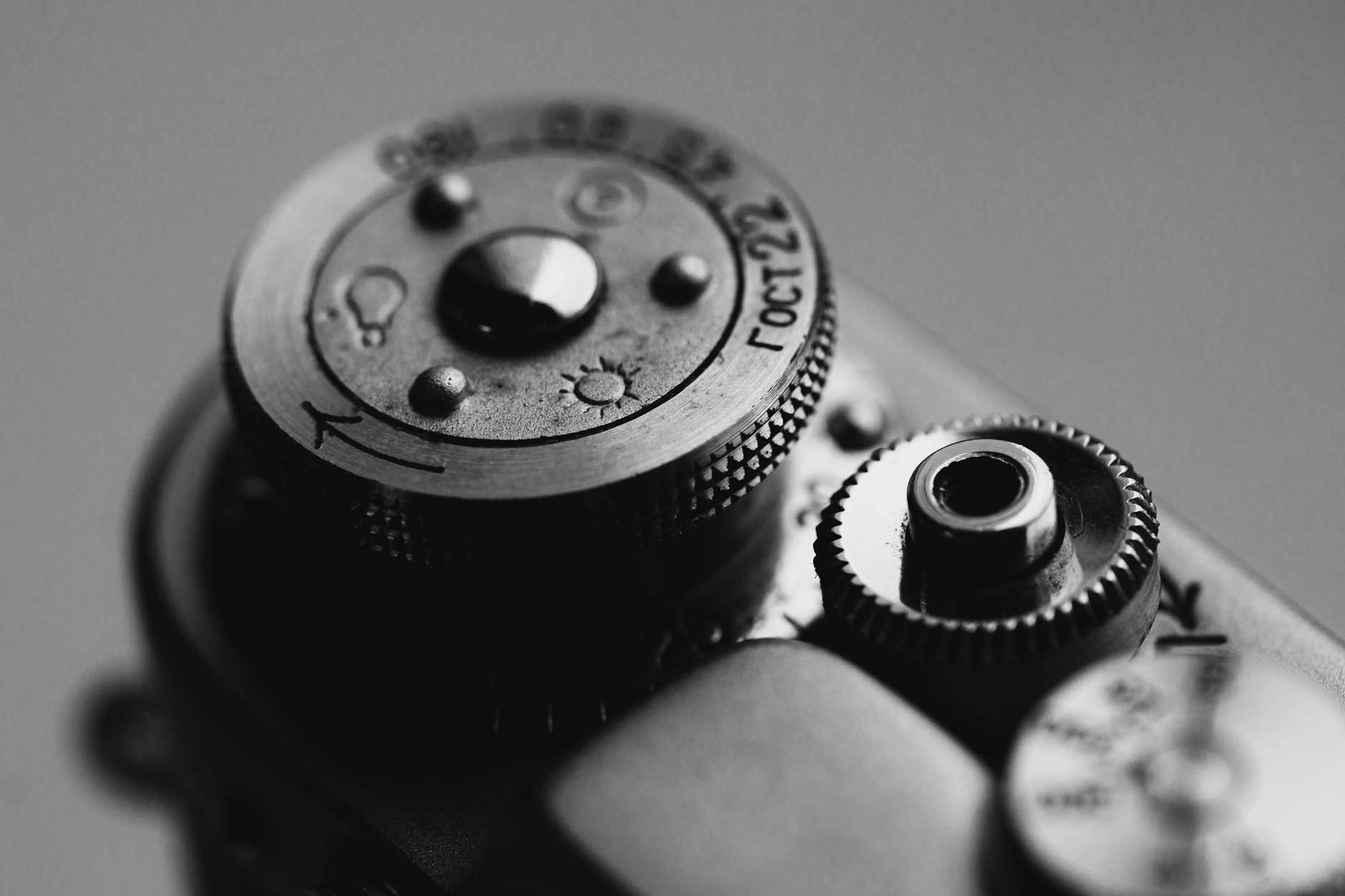 Detailed black and white close-up of a vintage camera dial showcasing its retro design.