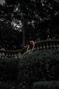 一个孤独的女人俯身在郁郁葱葱的花园露台上，四周绿意环绕，唤起一种忧郁的氛围
