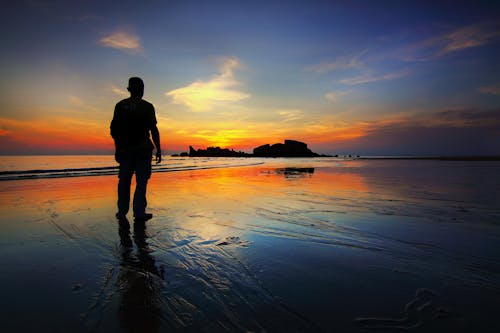 Free Silhouette of Man Standing on Seashore Stock Photo