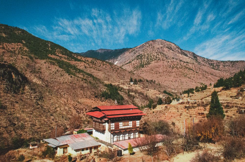 Casa tradicional bhutanesa de tejado rojo en un valle del Himalaya