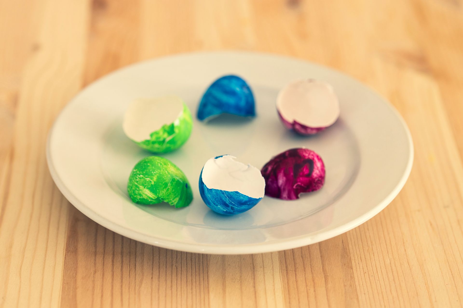 Colorful eggshells on a white plate, perfect for festive spring themes.
