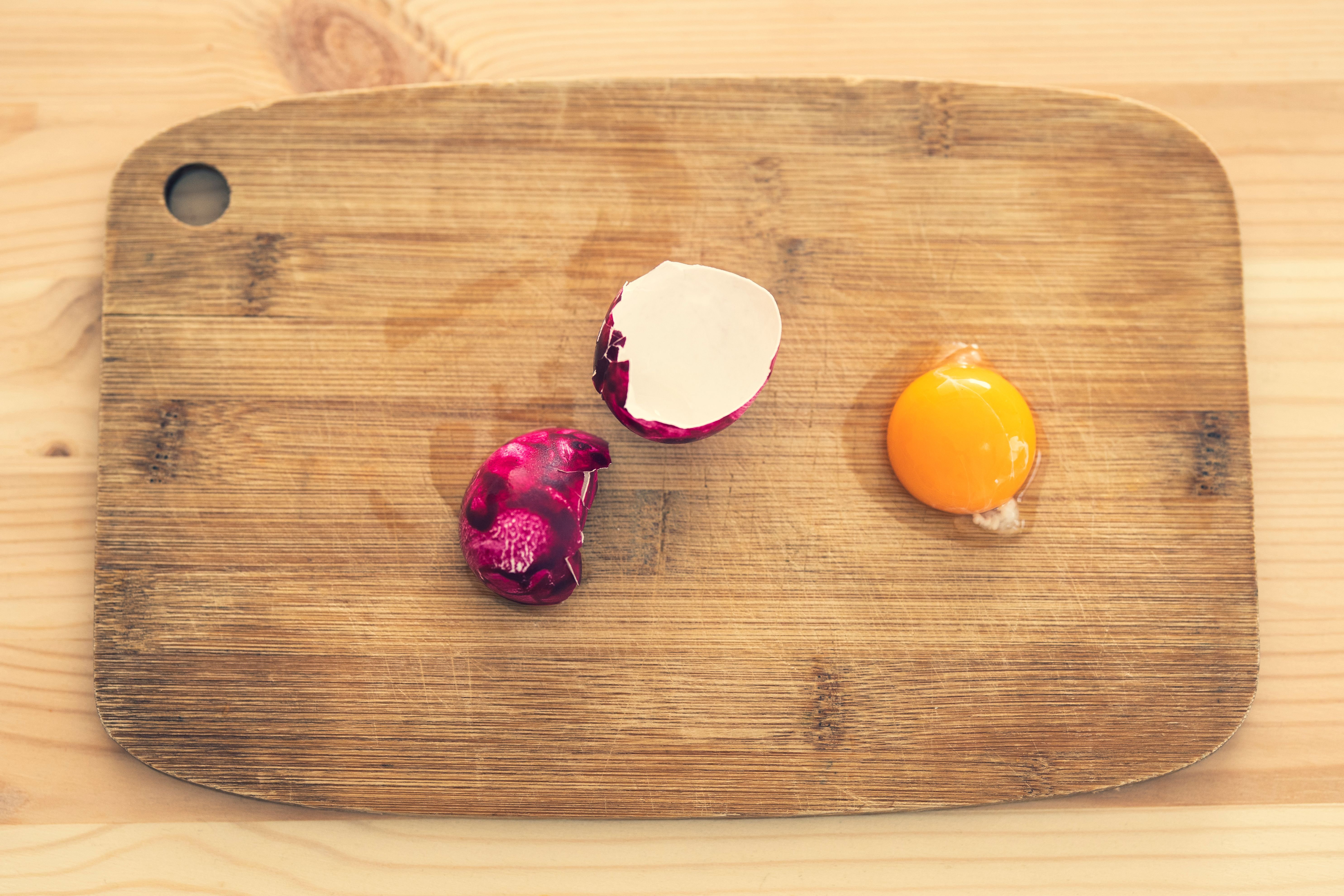 A fresh egg yolk and radish arranged on a wooden cutting board.