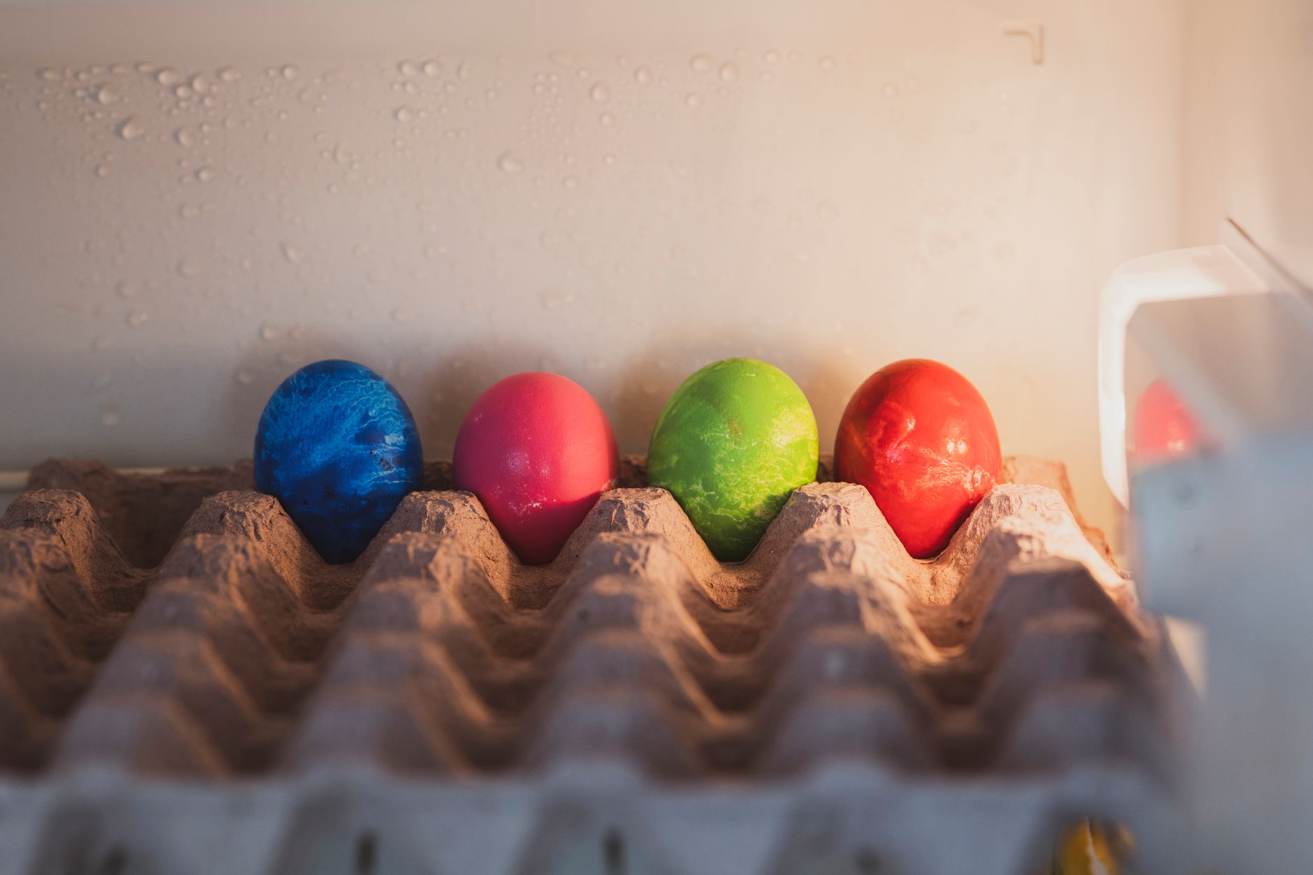 Three fresh eggs in a white ceramic bowl with a checkered tablecloth
